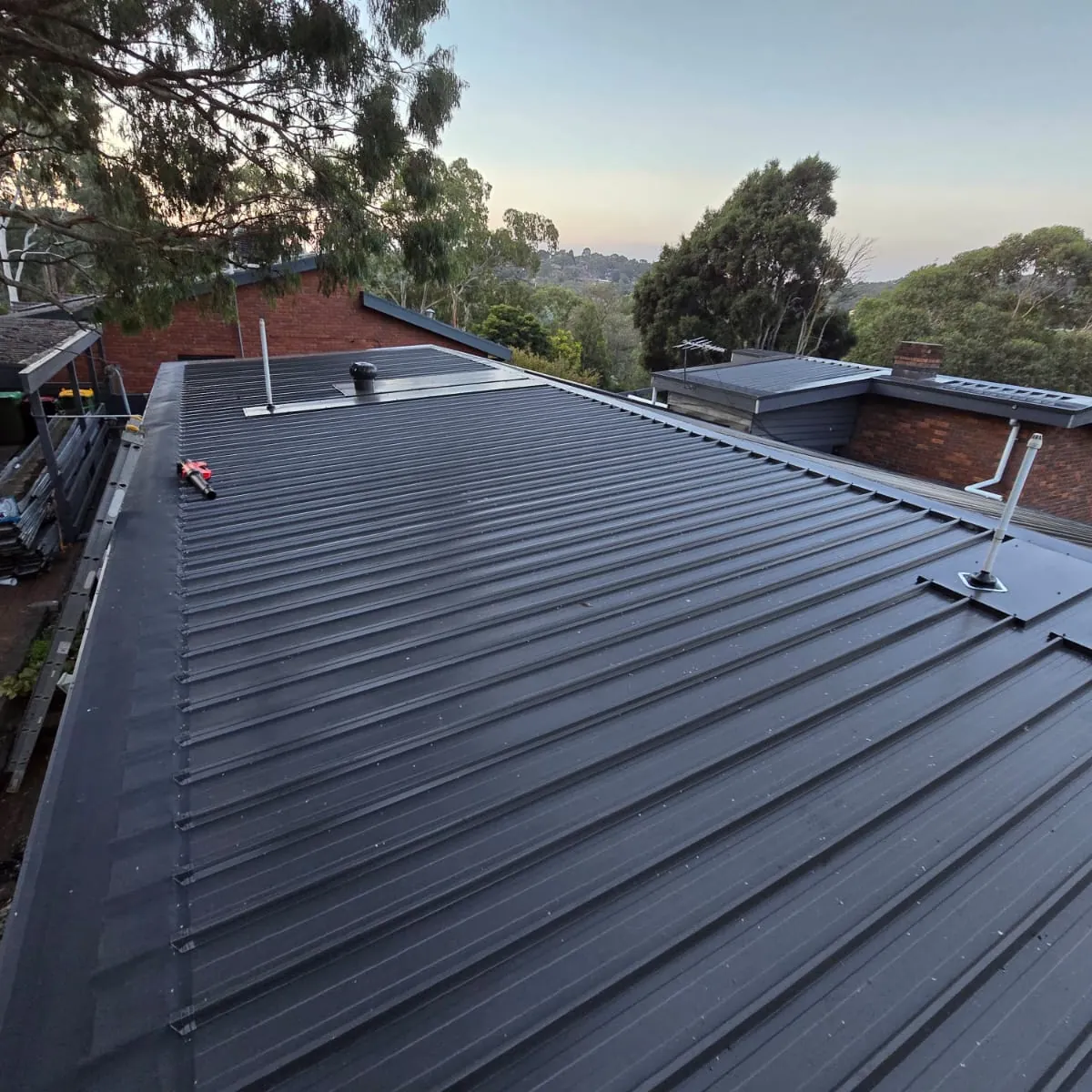 Charcoal metal roof on a brick home at dusk