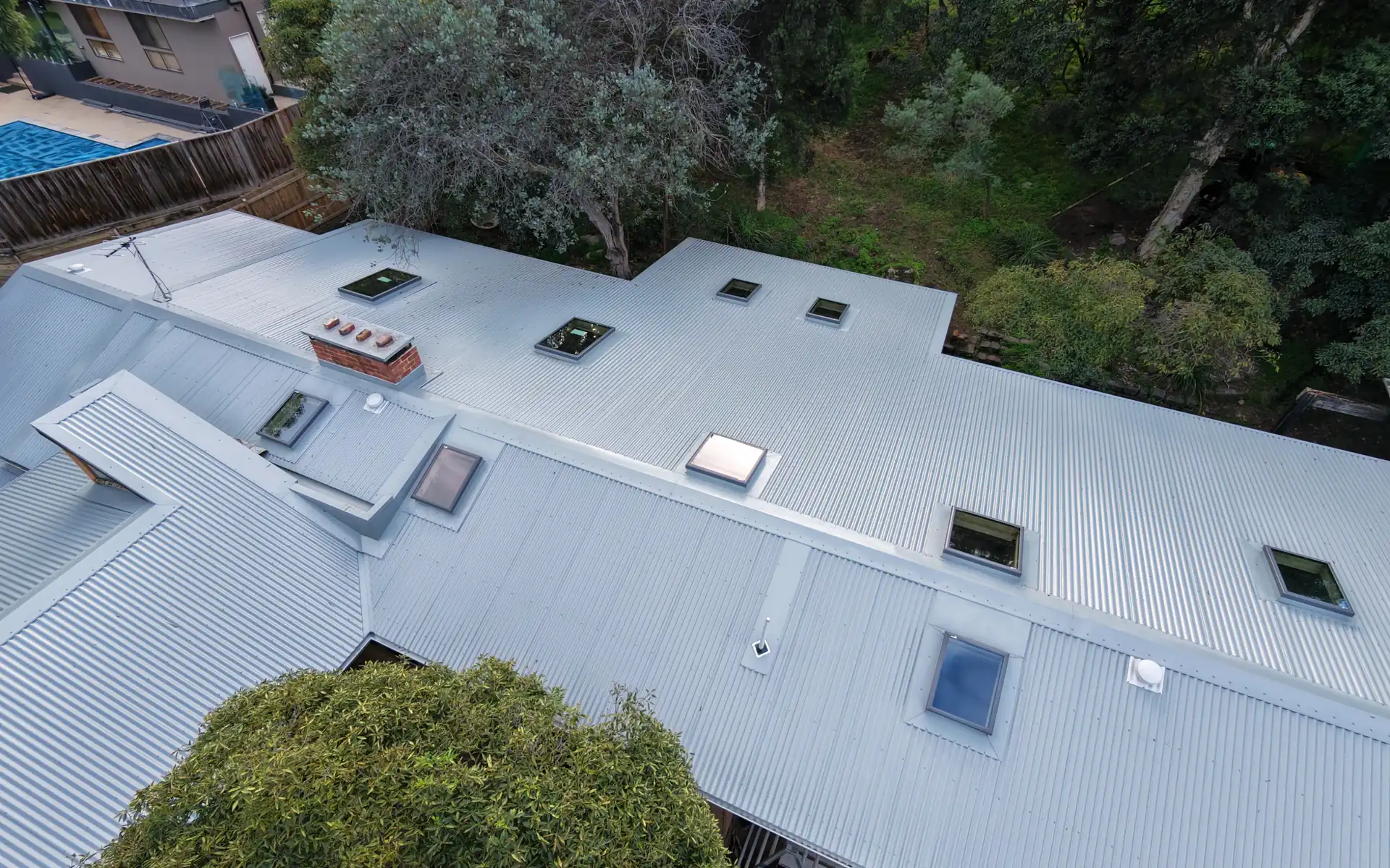 Newly installed metal roof on a large home surrounded by bushland