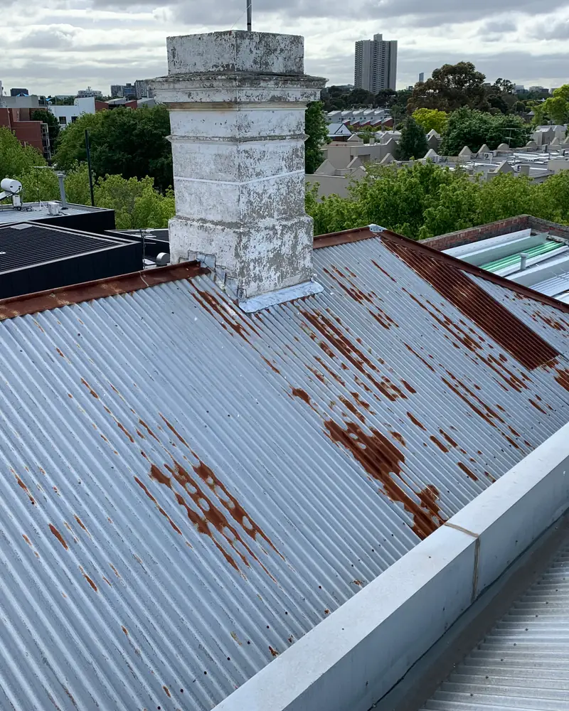Rusted corrugated metal roof with a brick chimney
